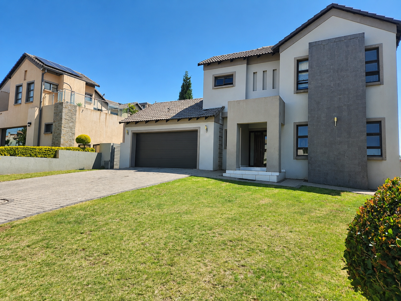 Modern double-storey residential home featuring a paved driveway, double garage, and striking stone-clad architectural facade elements.