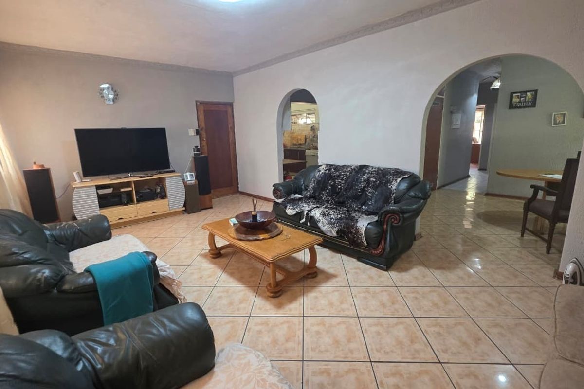 Spacious living room featuring tiled flooring and distinctive arched doorways leading to adjacent areas, offering a functional layout with neutral wall finishes.