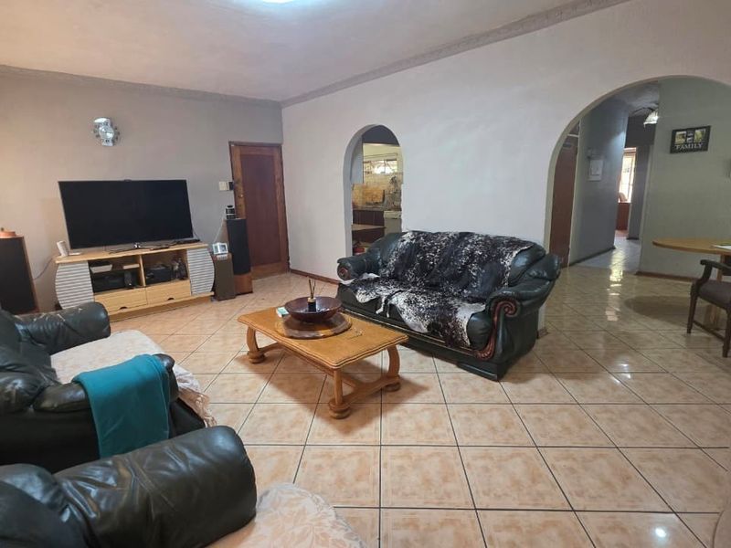 Spacious living room featuring tiled flooring and distinctive arched doorways leading to adjacent areas, offering a functional layout with neutral wall finishes.