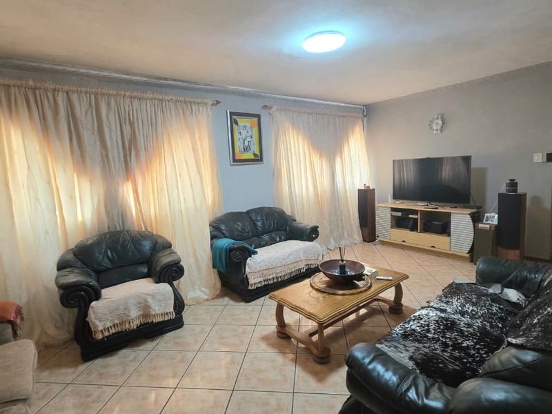 A living room featuring tiled flooring and ceiling lighting, requiring cosmetic updates to the wall and ceiling finishes to improve the overall aesthetic.