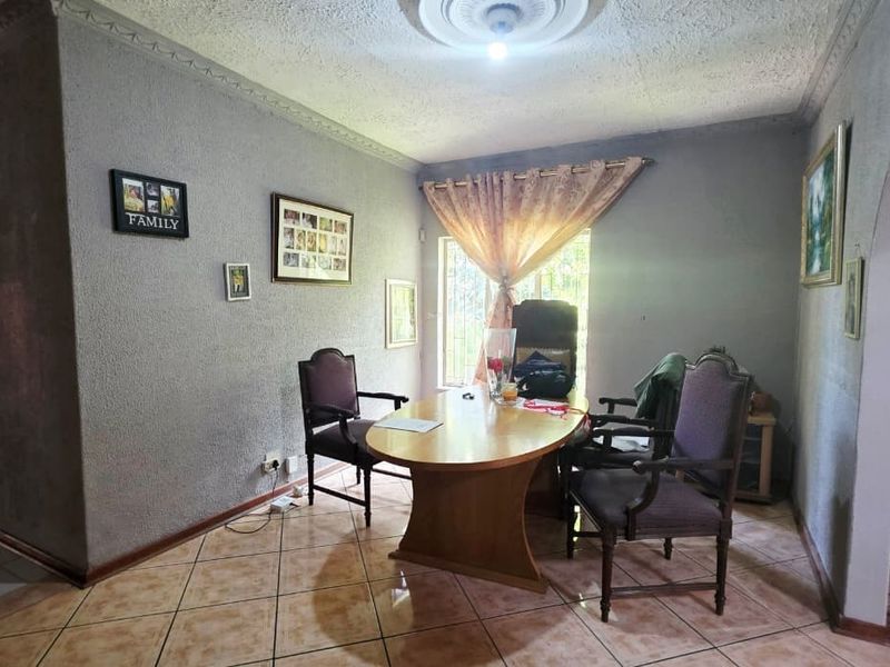 A living area featuring ceramic tile flooring, textured walls, and a decorative ceiling rose, offering a functional space with potential for modern updates.