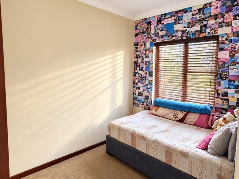 A bedroom featuring carpeted flooring, coving, and a window fitted with wooden venetian blinds.