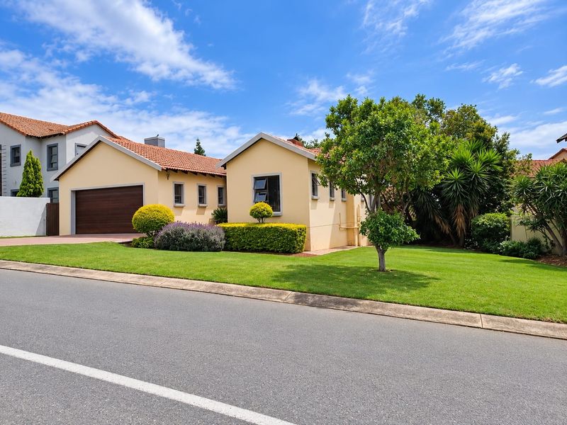 A well-maintained single-story residential property featuring a terracotta tiled roof, double garage, and a neat, landscaped front garden.