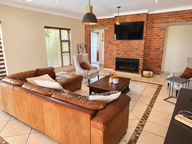 Spacious living room featuring an exposed brick fireplace, tiled flooring with a decorative border, and recessed lighting, creating a warm and inviting atmosphere.
