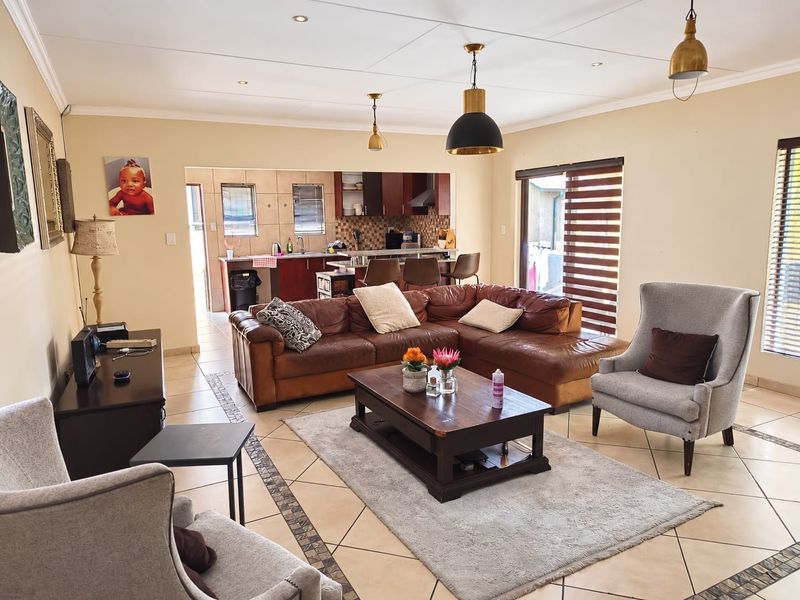Spacious open-plan living area featuring tiled floors, recessed lighting, and a seamless transition to a functional kitchen with island seating.