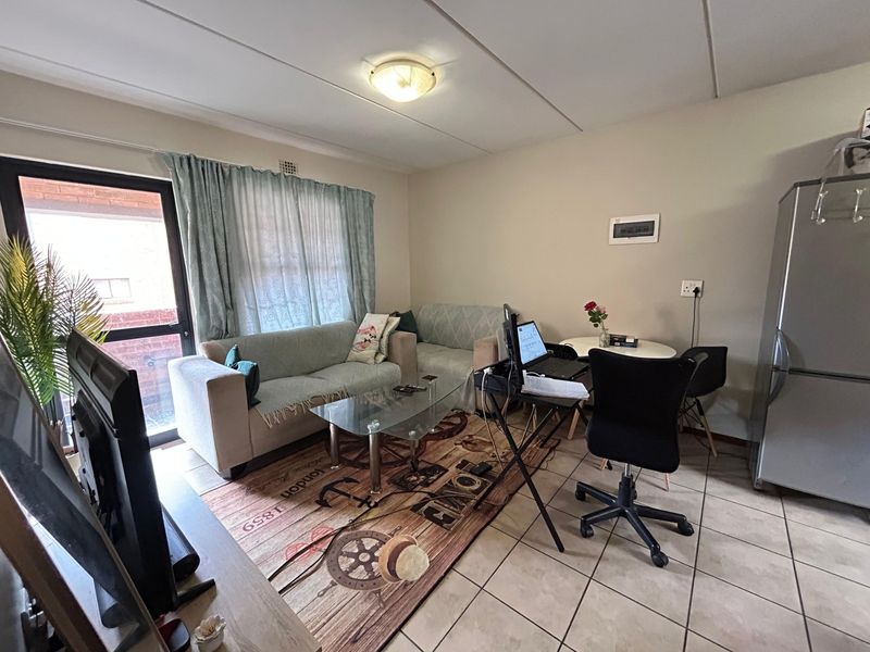 A functional living area featuring tiled flooring, a ceiling light fixture, and a sliding glass door providing access to the exterior.