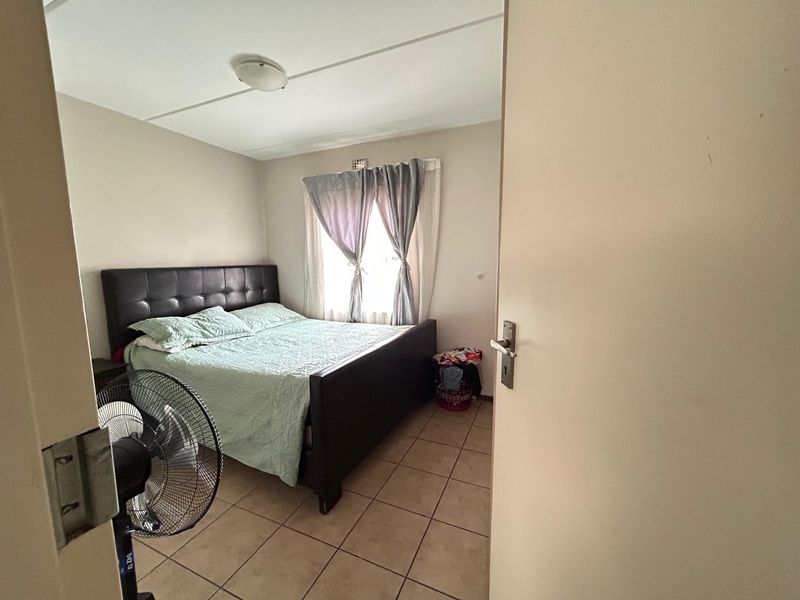 A standard bedroom featuring tiled flooring and a central ceiling light fixture, viewed from the doorway.