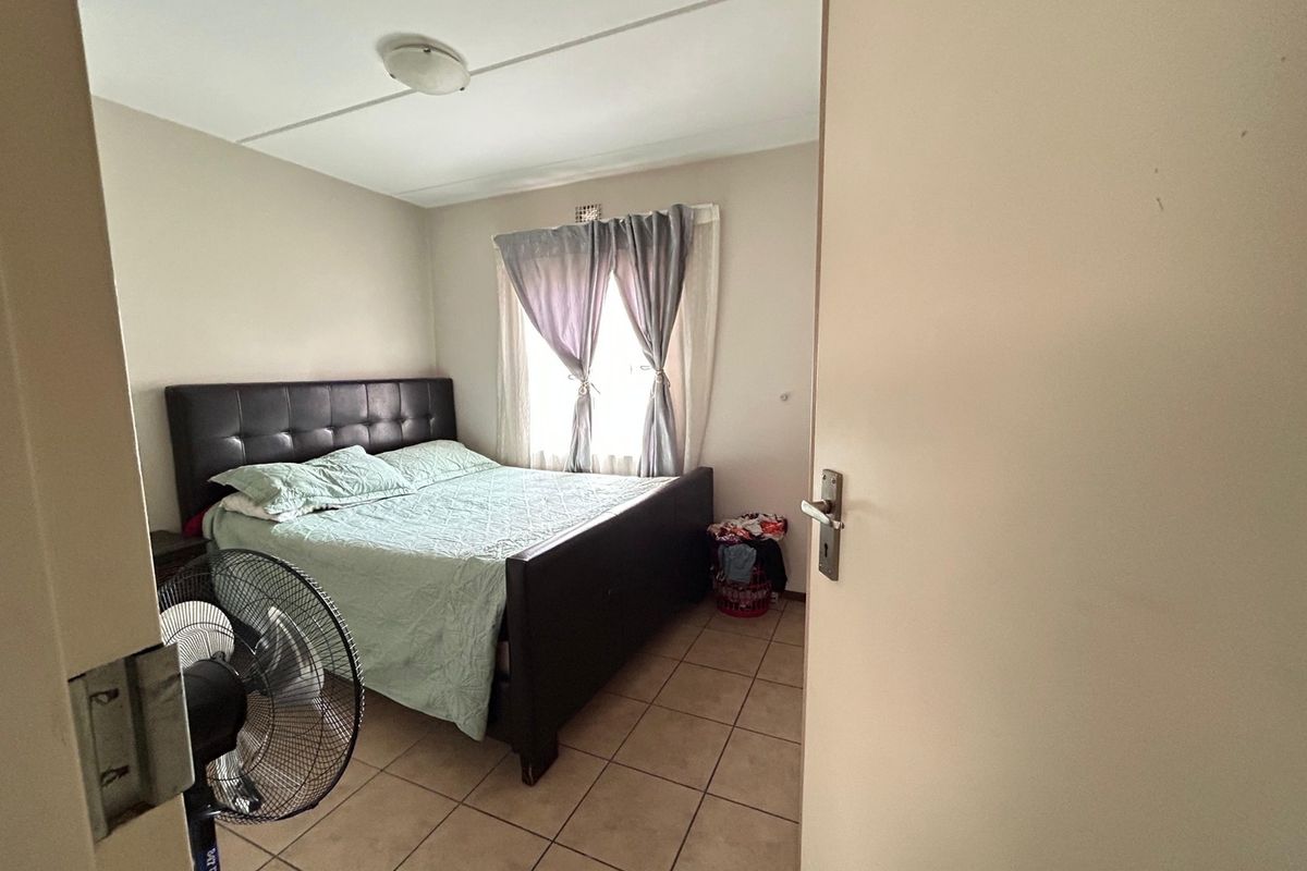 A standard bedroom featuring tiled flooring and a central ceiling light fixture, viewed from the doorway.