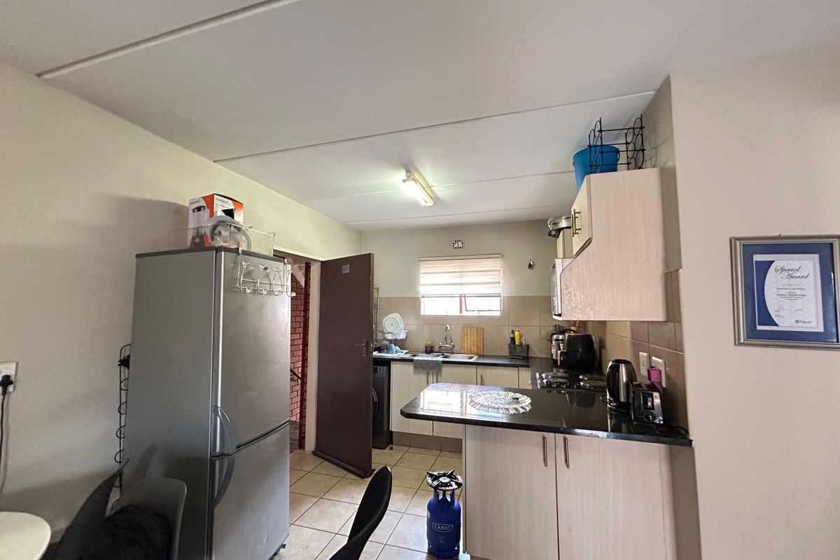 A functional kitchen featuring built-in cabinetry, granite countertops, and tiled flooring, offering a practical layout for daily meal preparation.