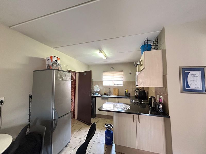 A functional kitchen featuring built-in cabinetry, granite countertops, and tiled flooring, offering a practical layout for daily meal preparation.