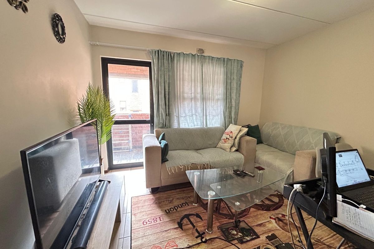 A functional living room featuring tiled flooring and a glass sliding door providing access to the exterior.
