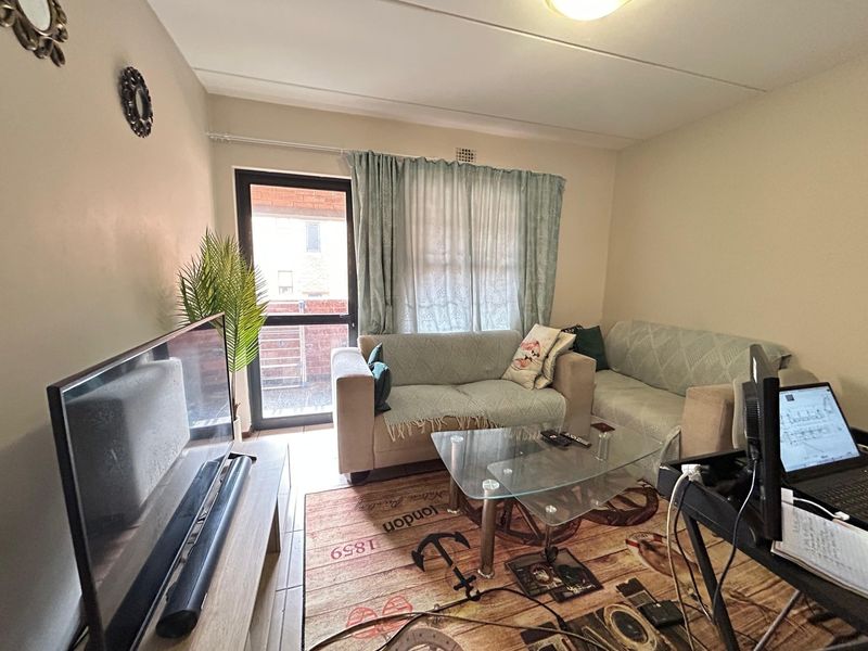 A functional living room featuring tiled flooring and a glass sliding door providing access to the exterior.