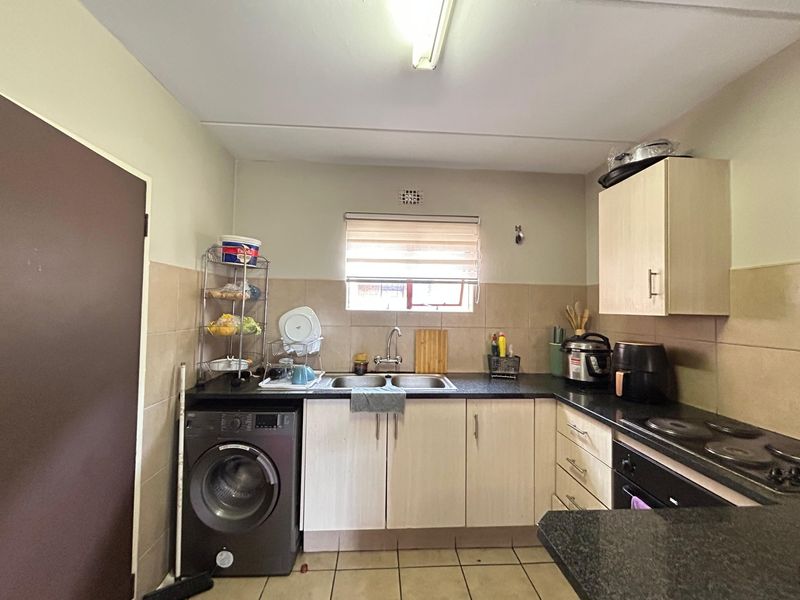 Functional kitchen featuring granite countertops, built-in oven and hob, double bowl sink, and ample cabinetry with tiled backsplash and flooring.
