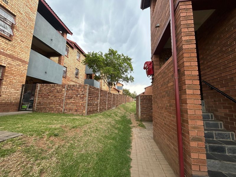 Exterior view of the apartment complex featuring face brick architecture, paved walkways, and communal garden areas between the residential blocks.