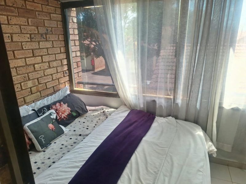A bedroom featuring an exposed brick wall and a large window that provides natural light and an exterior view.