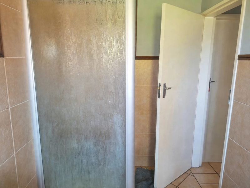 A functional bathroom space featuring a shower enclosure with tiled walls and flooring, presenting an opportunity for cosmetic updates.