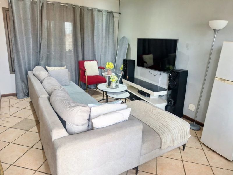 A living room featuring ceramic floor tiles and neutral wall finishes, providing a functional space for relaxation and entertainment.