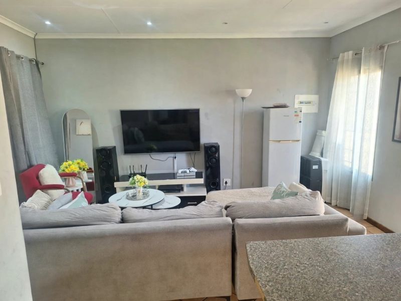 A comfortable living room area featuring tiled flooring, recessed ceiling lighting, and a neutral wall finish, providing a functional space for relaxation.