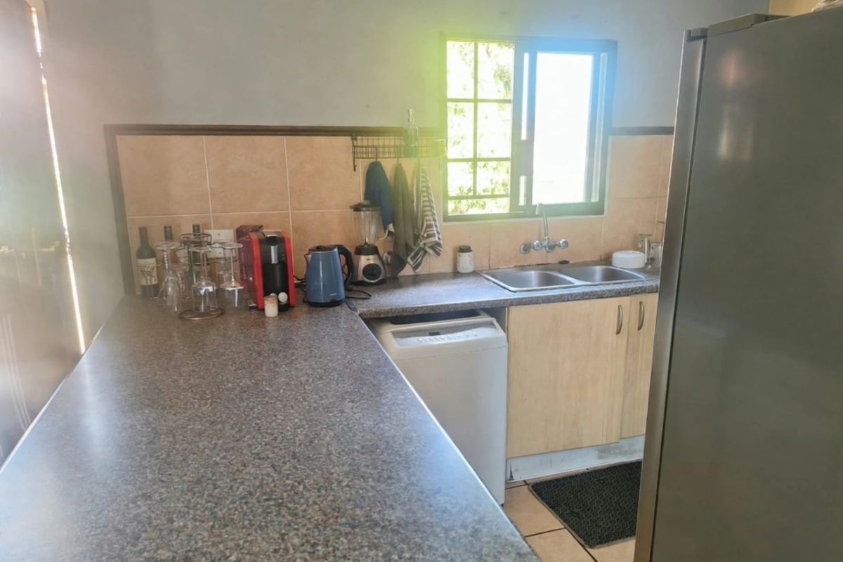 A functional kitchen featuring laminate countertops, a double basin sink, tiled backsplash, and built-in cabinetry with natural light from the window.
