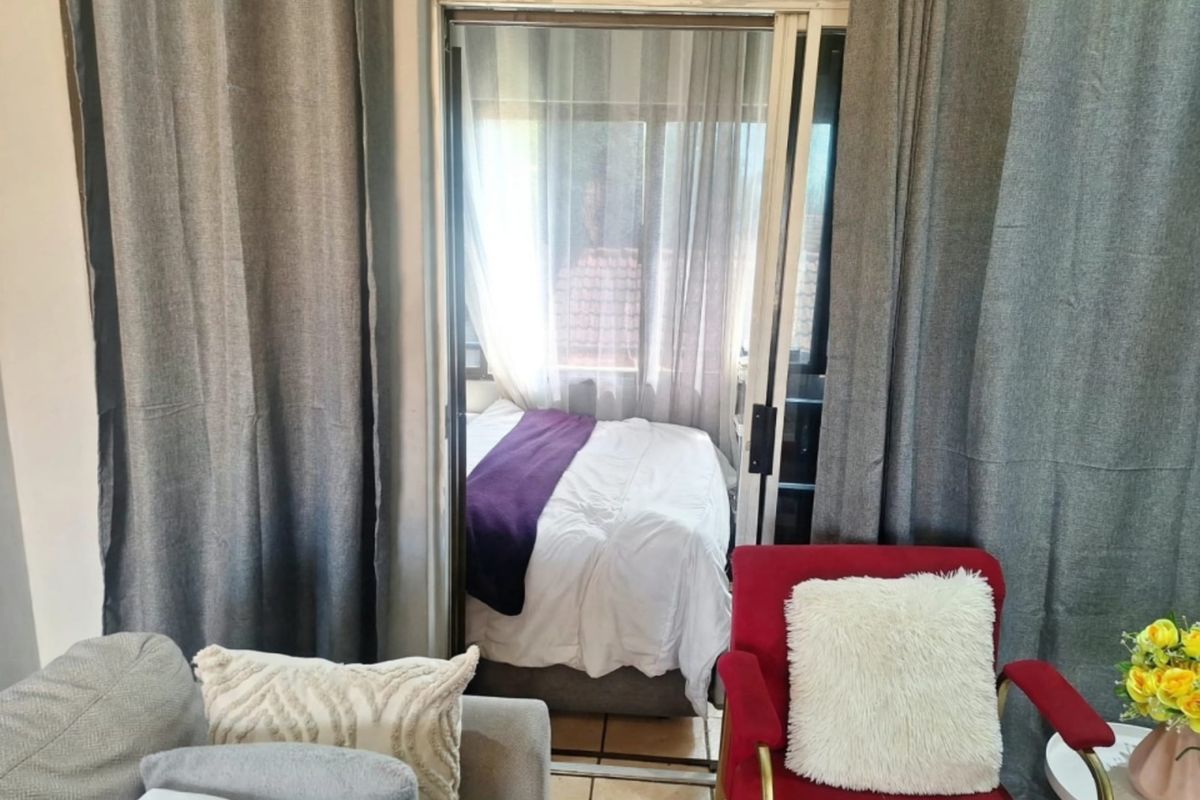 A bedroom space accessible via a sliding glass door, featuring tiled flooring and neutral wall finishes.