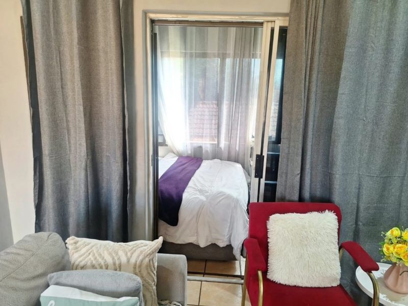 A bedroom space accessible via a sliding glass door, featuring tiled flooring and neutral wall finishes.
