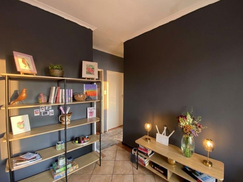 A living area featuring dark painted walls, tiled flooring, and decorative cove cornicing, providing a neutral base for interior design updates.