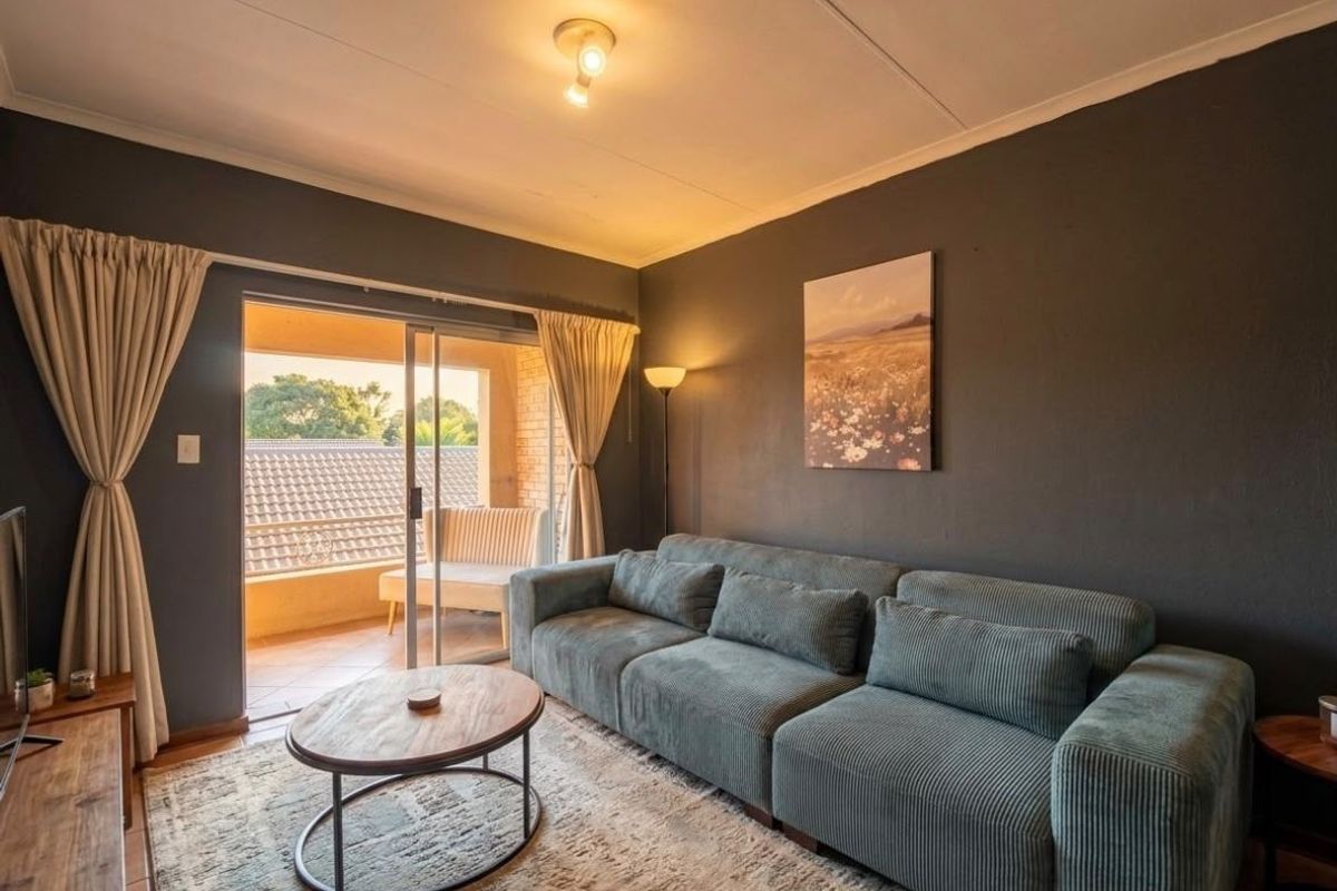 A comfortable living room featuring dark painted walls, tiled flooring, and a sliding glass door providing access to an outdoor balcony area.