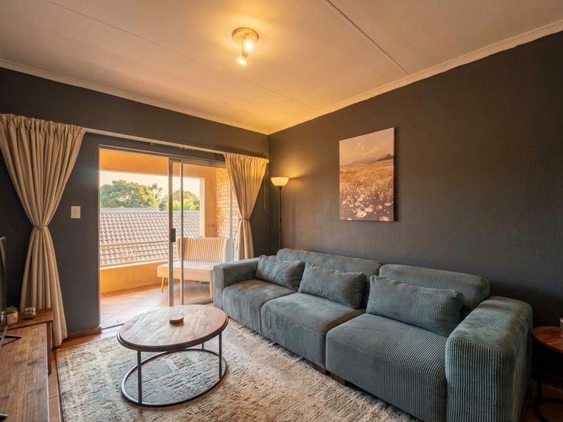 A comfortable living room featuring dark painted walls, tiled flooring, and a sliding glass door providing access to an outdoor balcony area.