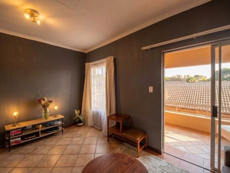 A living room featuring tiled flooring, dark painted walls, and a sliding glass door providing access to an outdoor balcony area.