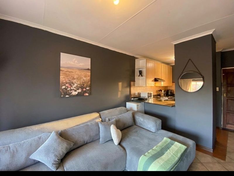 Open plan living area featuring a compact kitchen with built-in cabinetry and tiled flooring, seamlessly connected to the lounge space.