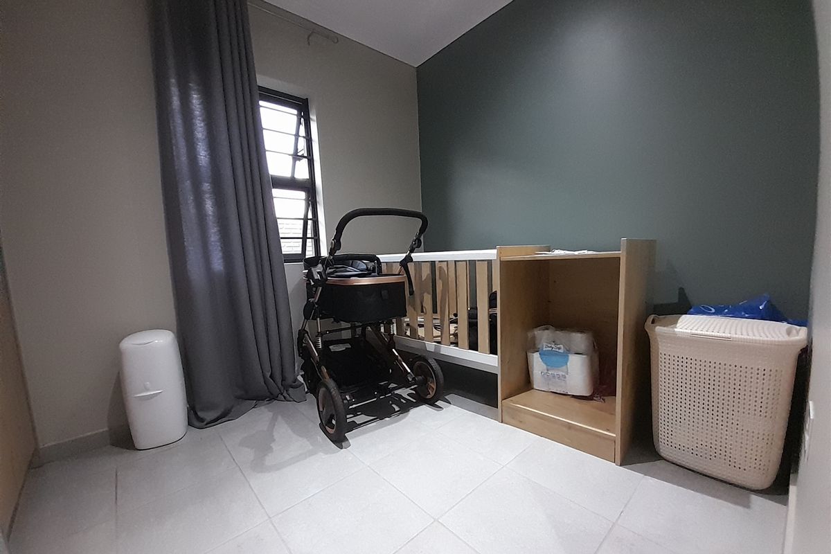 A bedroom featuring tiled flooring and a window with security bars, finished with a neutral and accent wall color scheme.