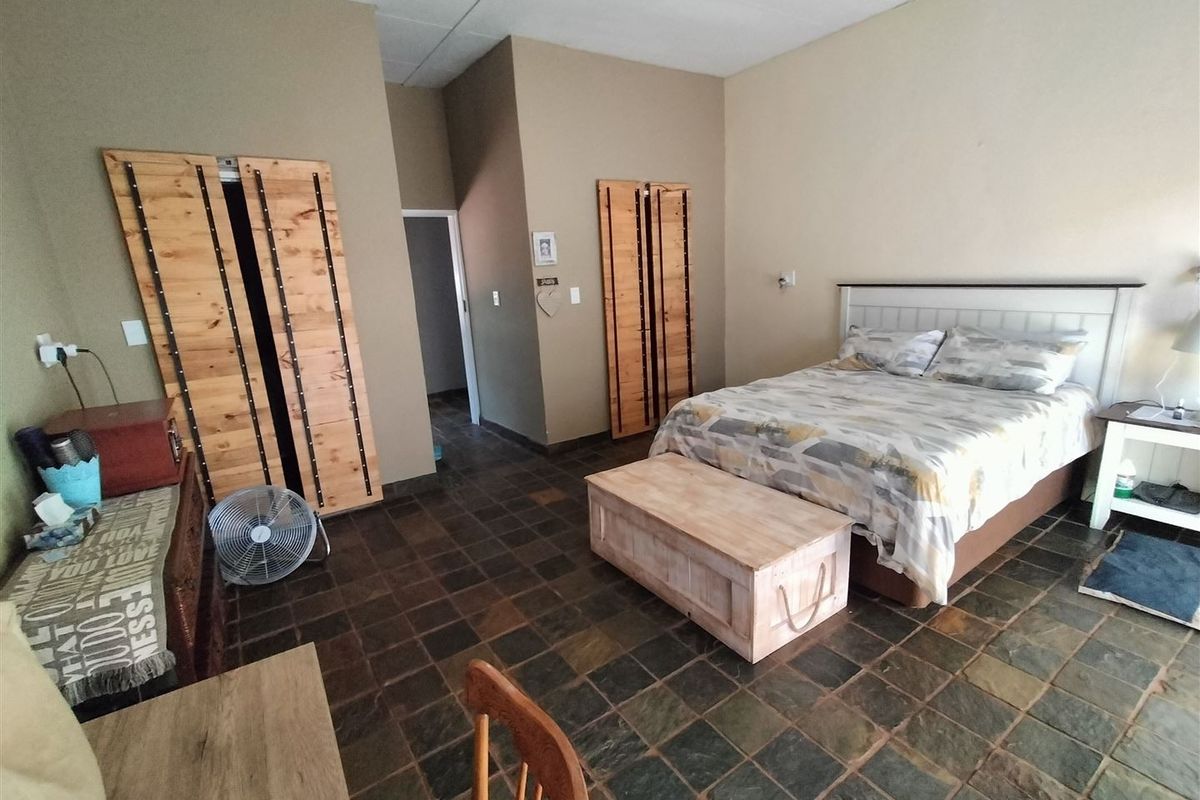 Spacious bedroom featuring rustic wooden built-in cupboards and durable slate tile flooring, offering a comfortable and functional living space.