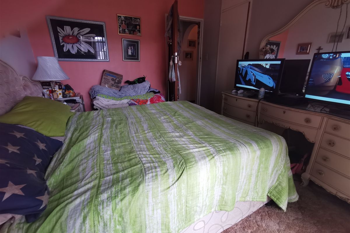 A bedroom featuring a built-in wardrobe and carpeted flooring, currently decorated with vibrant wall paint.