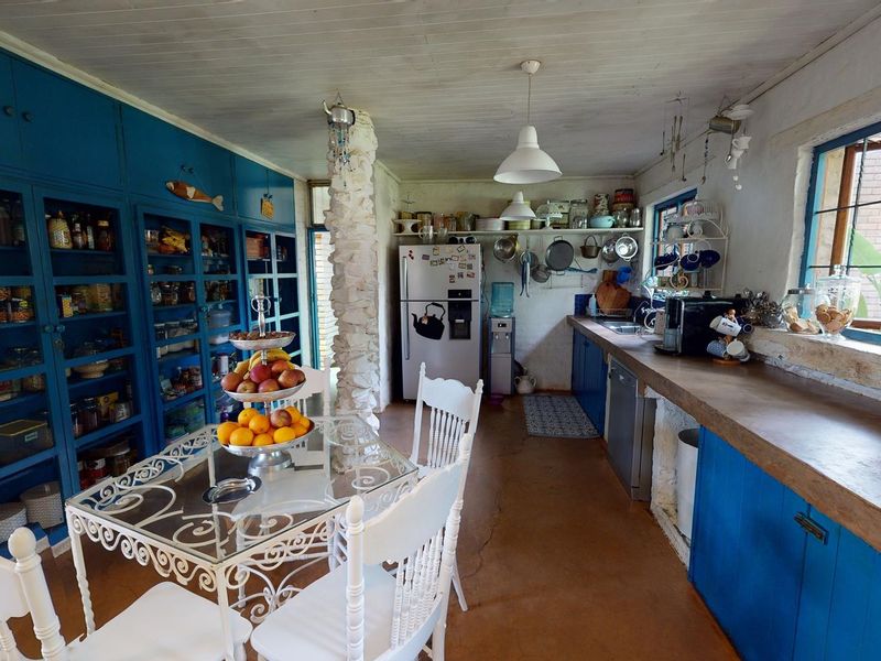 Rustic kitchen featuring blue built-in cabinetry, a unique stone-clad pillar, concrete countertops, and a timber ceiling, offering a charming, lived-in aesthetic.