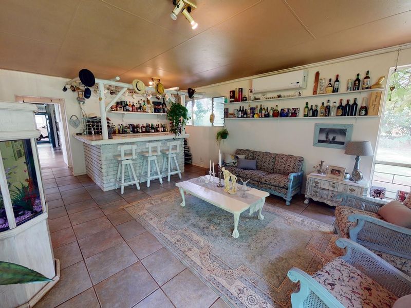 A dedicated bar area featuring a built-in brick-base counter, wall-mounted shelving for display, and tiled flooring, creating a functional entertainment space.
