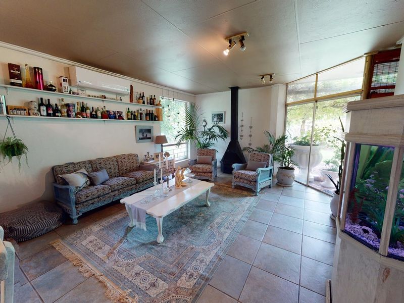 Spacious living room featuring tiled flooring, a freestanding fireplace, and large sliding glass doors providing natural light and access to the outdoor area.