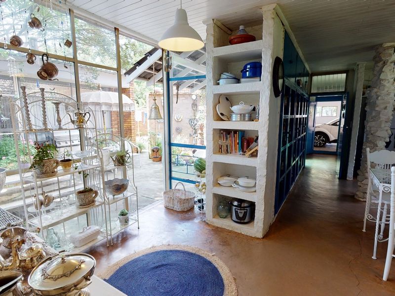 Open-plan living area featuring large glass windows, built-in shelving, and exposed stone elements, creating a bright and connected space with direct patio access.