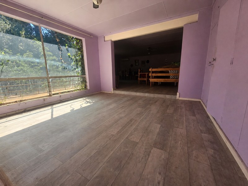 Spacious living area featuring large windows, laminate flooring, and built-in storage cupboards, offering a bright and open layout.