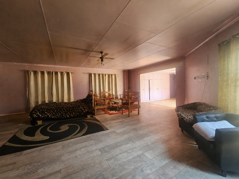 Spacious living area featuring tiled flooring, a ceiling fan, and integrated built-in storage cupboards, offering a versatile layout for family living.