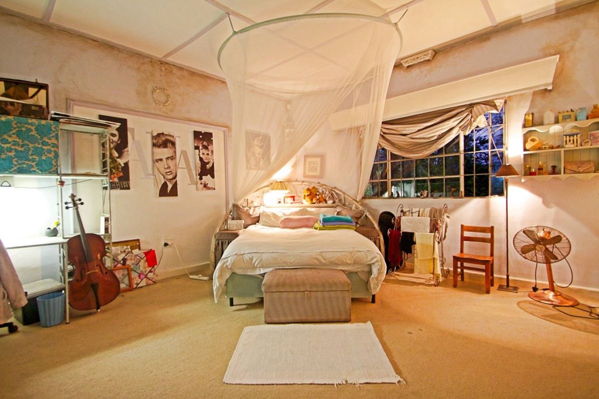A spacious bedroom featuring large multi-pane windows and carpeted flooring, currently requiring cosmetic updates to the wall finishes.
