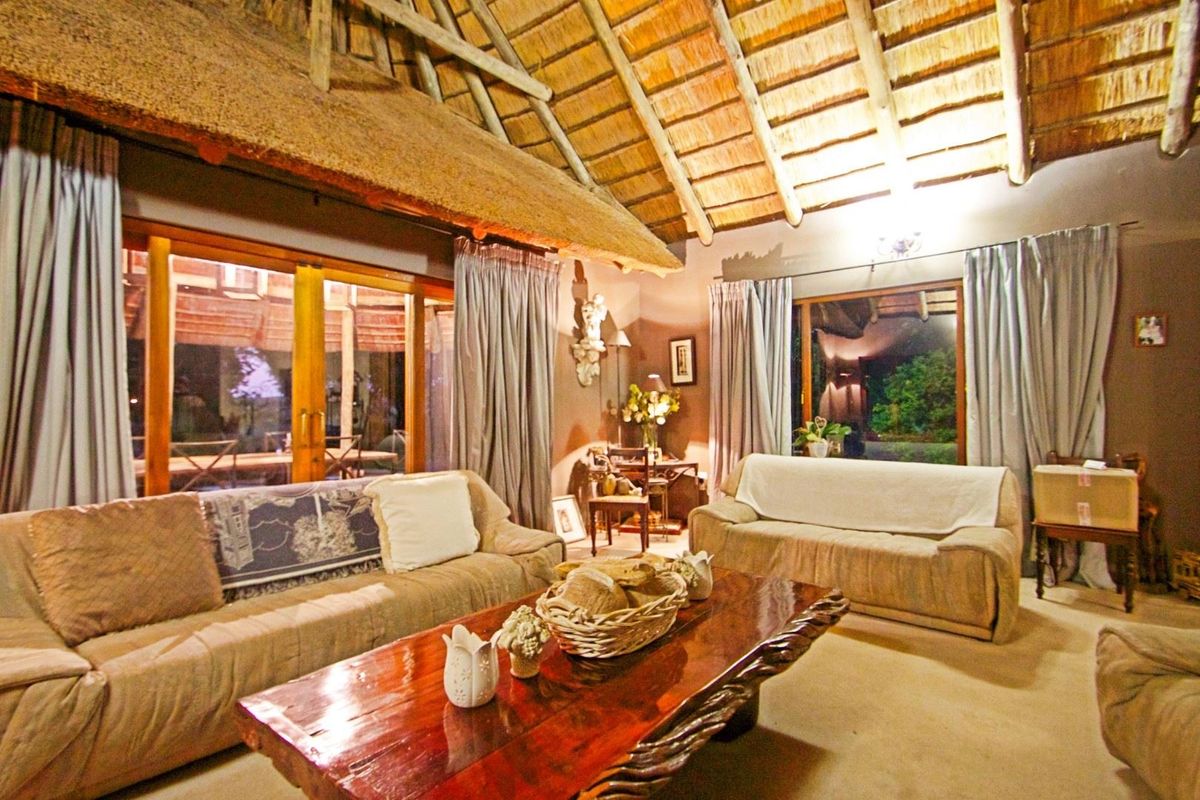 Spacious living room featuring a high vaulted thatched roof with exposed timber rafters and large sliding glass doors providing access to the outdoor area.
