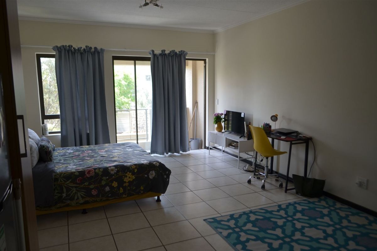 A spacious bedroom featuring tiled flooring and a sliding glass door providing access to a private balcony.