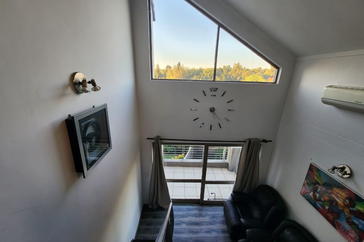 Spacious living area featuring a dramatic vaulted ceiling, large triangular window, and direct access to a private balcony with scenic views.