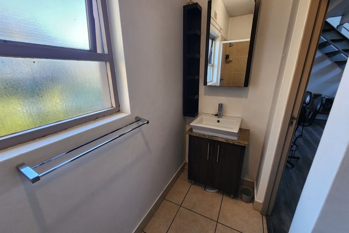A compact bathroom featuring a modern vessel sink on a granite-topped vanity cabinet, chrome fixtures, and tiled flooring with natural light from a frosted window.