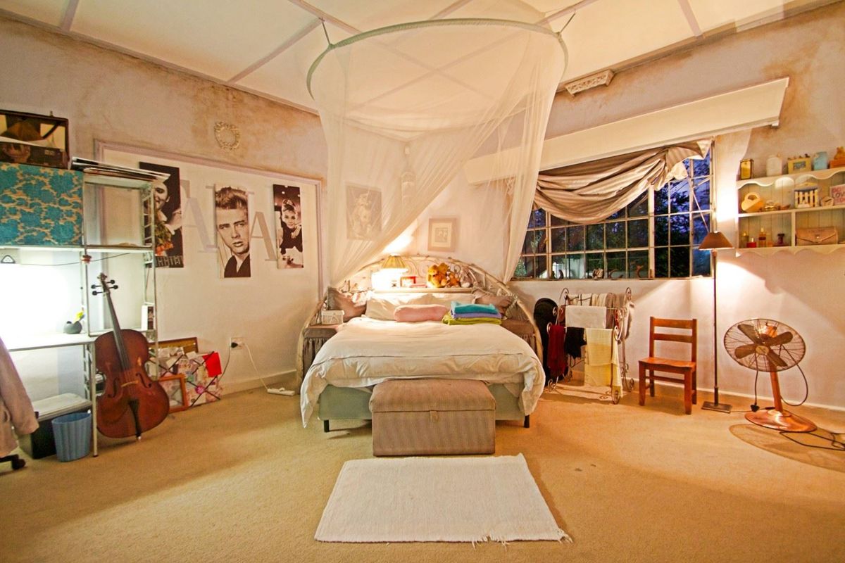 Spacious bedroom featuring large grid-pattern windows, exposed ceiling beams, and carpeted flooring, requiring cosmetic updates to the wall and ceiling finishes.