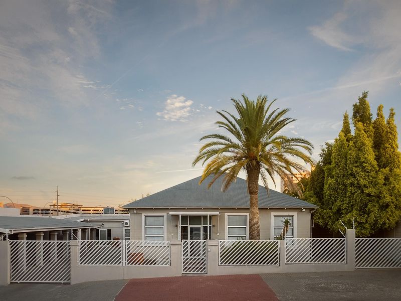 Front exterior view of the office property featuring a metal roof, secure perimeter fencing, and a paved driveway entrance.