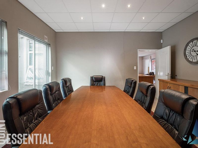 A professional boardroom or office space featuring a suspended ceiling with recessed lighting, venetian blinds, and built-in cabinetry.