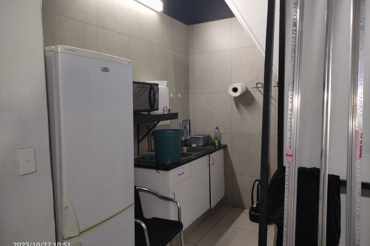A compact kitchenette area featuring tiled walls, a small sink, and built-in base cabinetry.