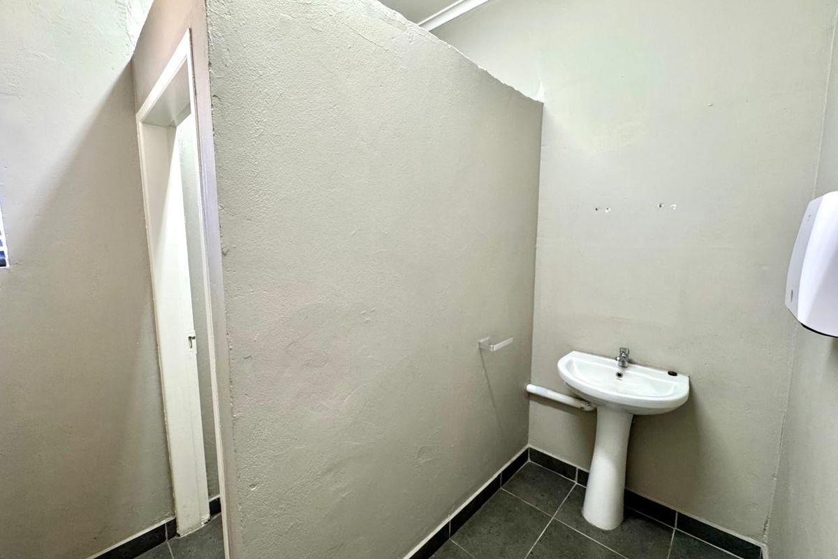 A functional bathroom space featuring a pedestal basin, tiled flooring, and a partition wall separating the area.