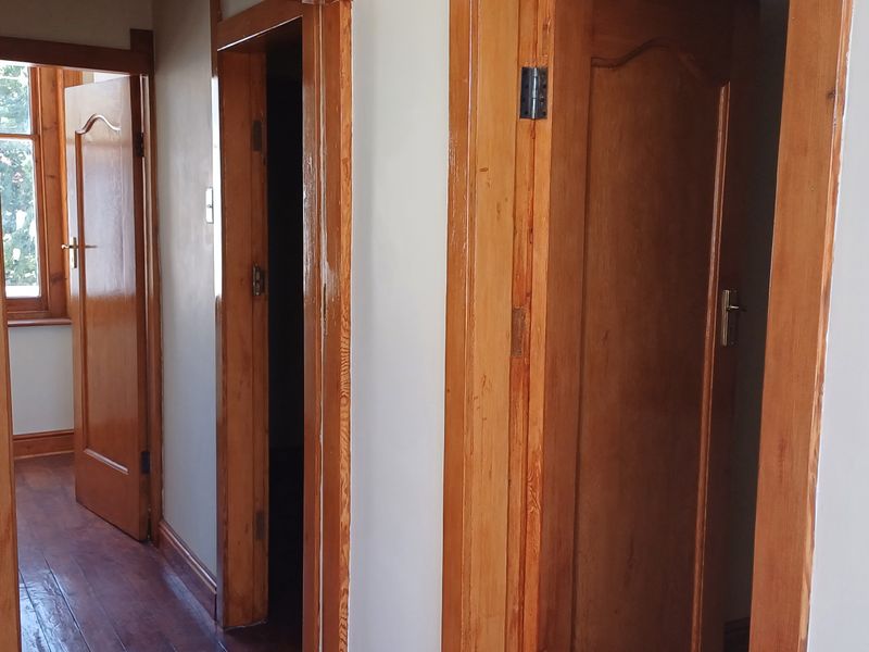 A hallway featuring timber door frames, wooden doors, and polished timber flooring.